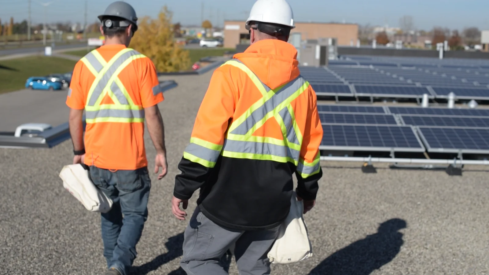 Field technicians walking onto a rooftop solar work area